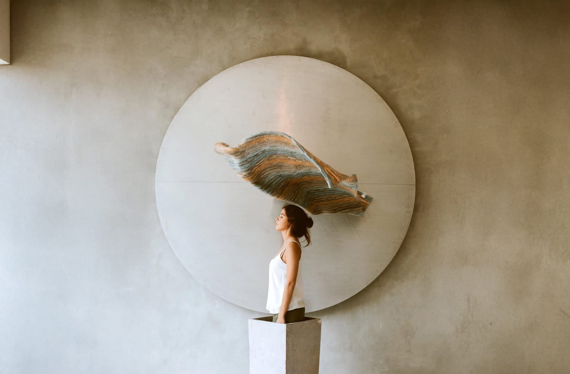 A guest in front of the concrete disc in the PULANG lobby
