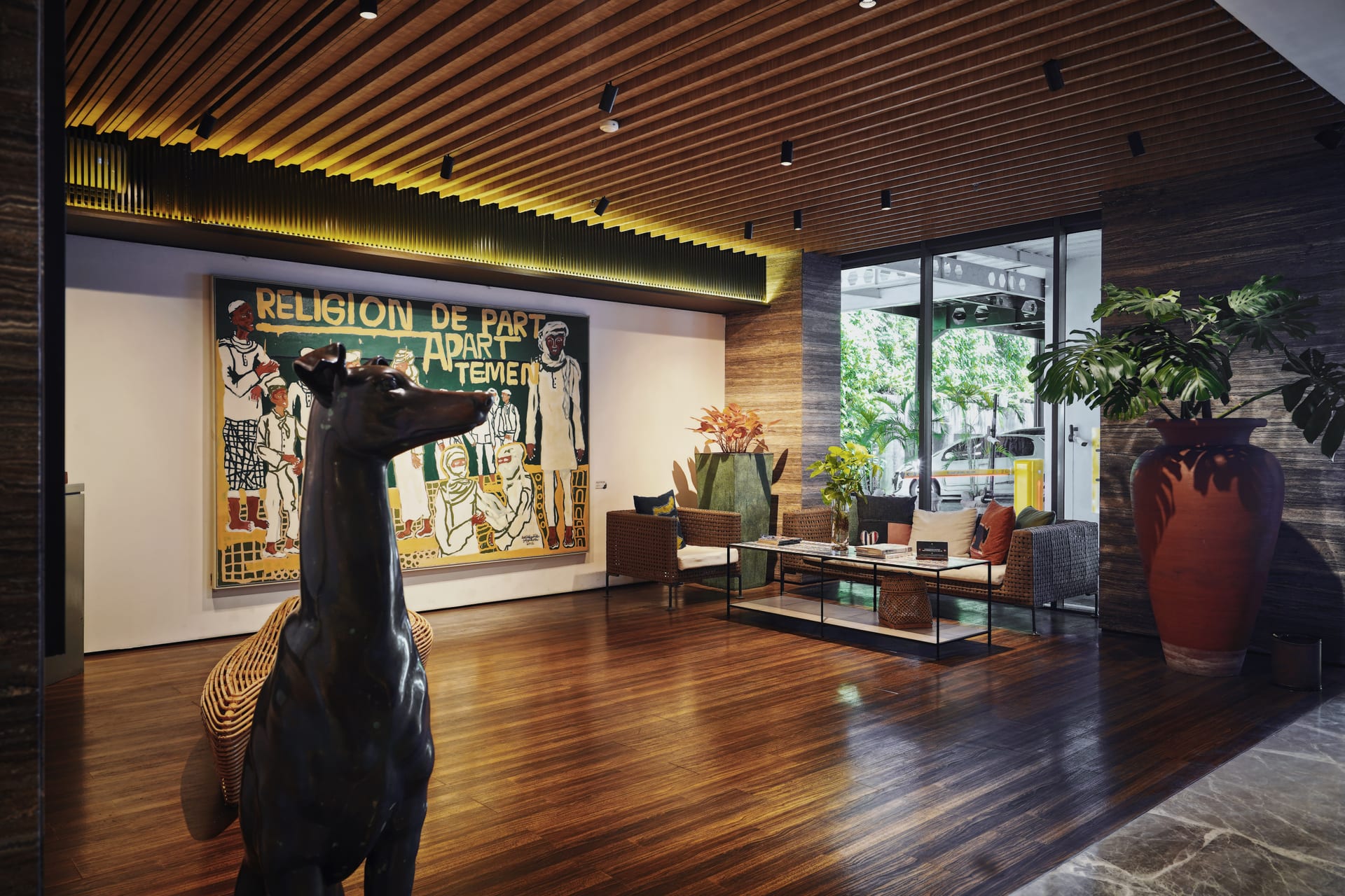 Black dog sculpture in front of a large mural in the PULANG ke UTTARA lobby seating area