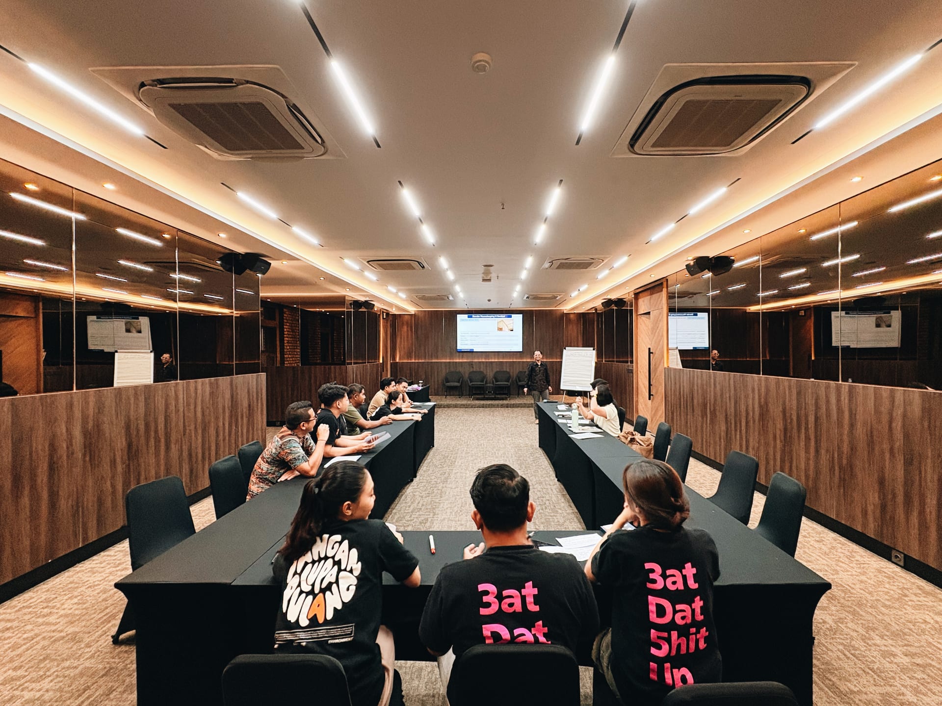 Workshop group at U-shape black-draped tables facing a presenter and screen in the Omong-Omong meeting room